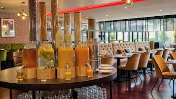 Un restaurante con barra, mesas redondas y zona de estar con sillas acolchadas.