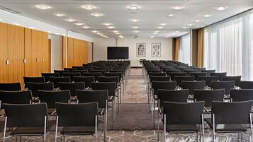 A conference room with rows of chairs, a large screen, and wooden lockers.