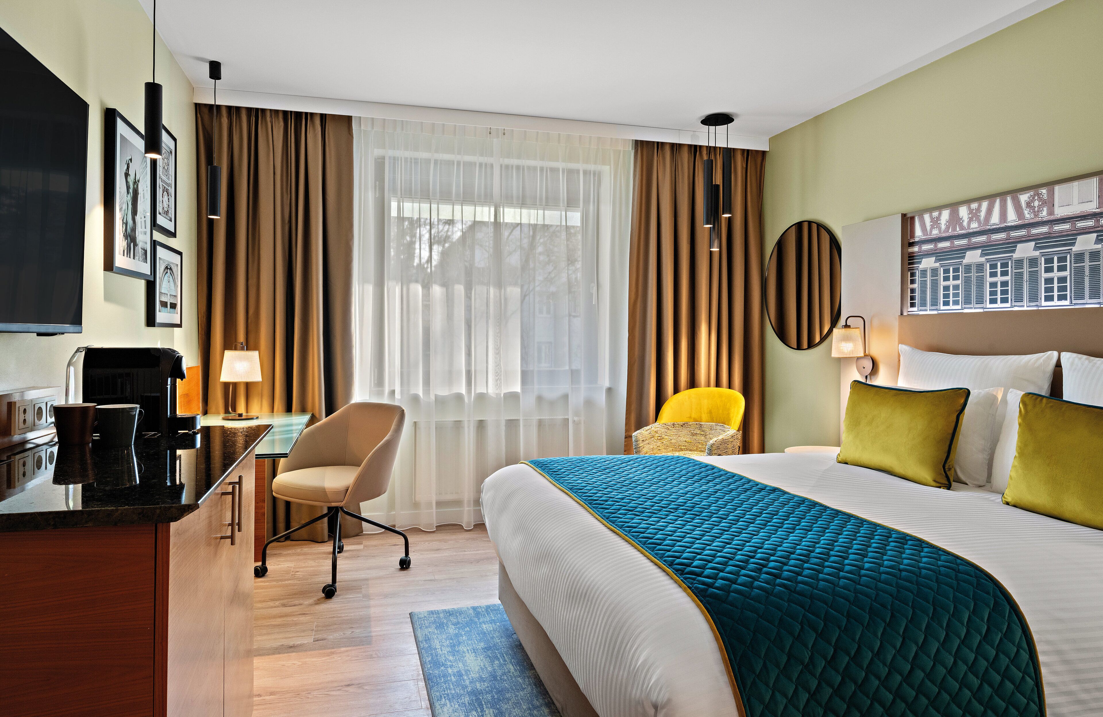 Habitación de hotel con una cama grande, un escritorio con silla, televisor y ventana con cortinas.