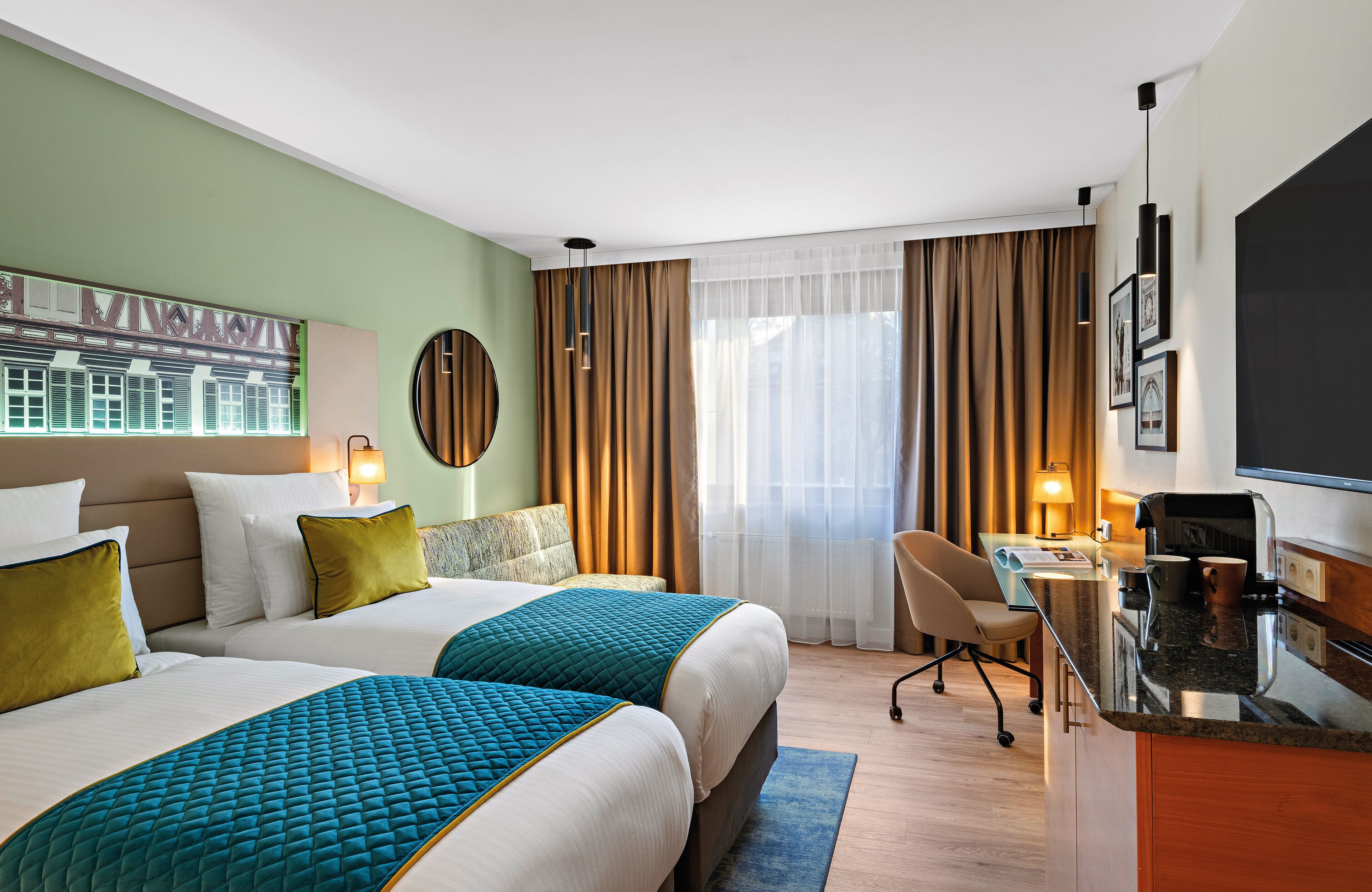 A hotel room with two beds, a desk, a chair, a TV, and a window with curtains.