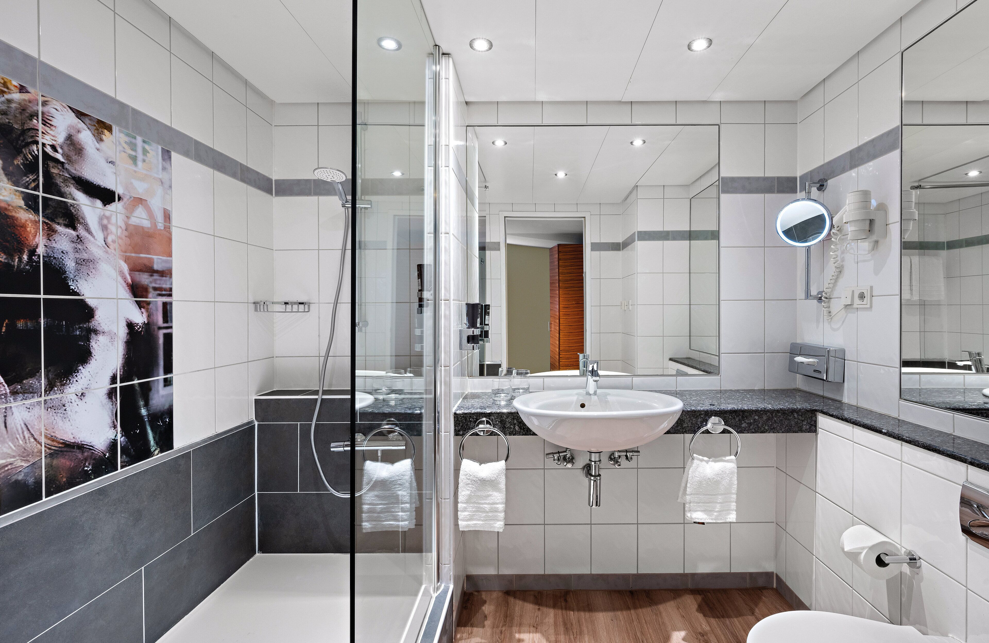A modern bathroom with a glass shower enclosure, a sink with a mirror, and a toilet.