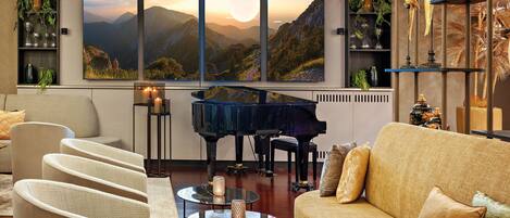 Una sala de estar moderna con un piano de cola, asientos cómodos y un amplio ventanal con vistas panorámicas.