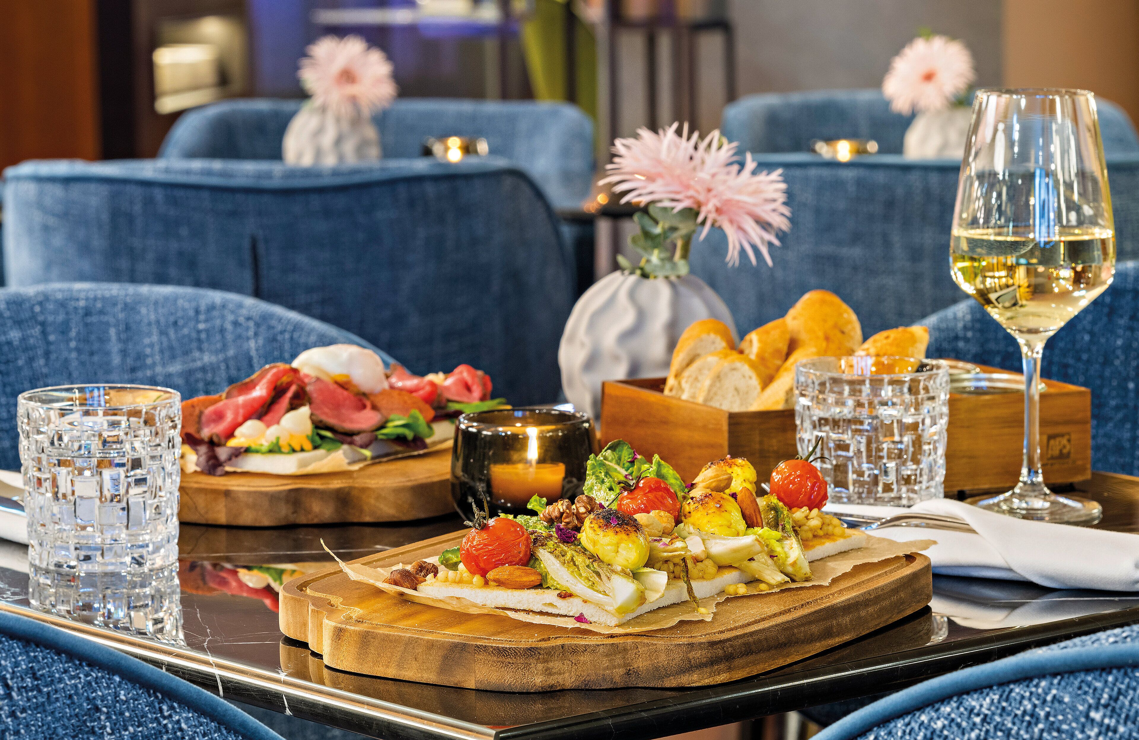 Een eettafel met diverse gerechten, glazen wijn en een vaas met bloemen.