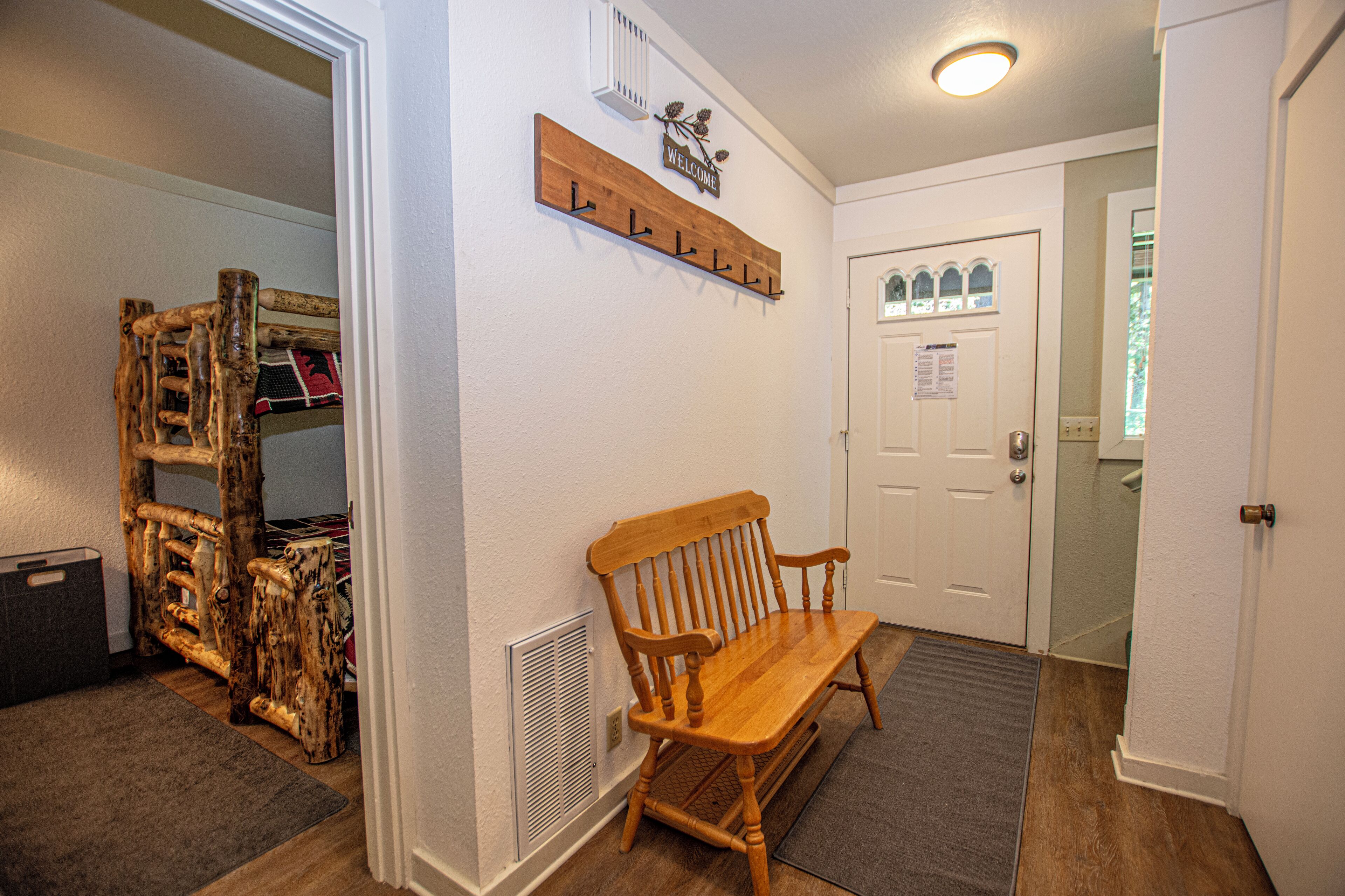 A hallway with a wooden bench, a coat rack, and a door with a window.