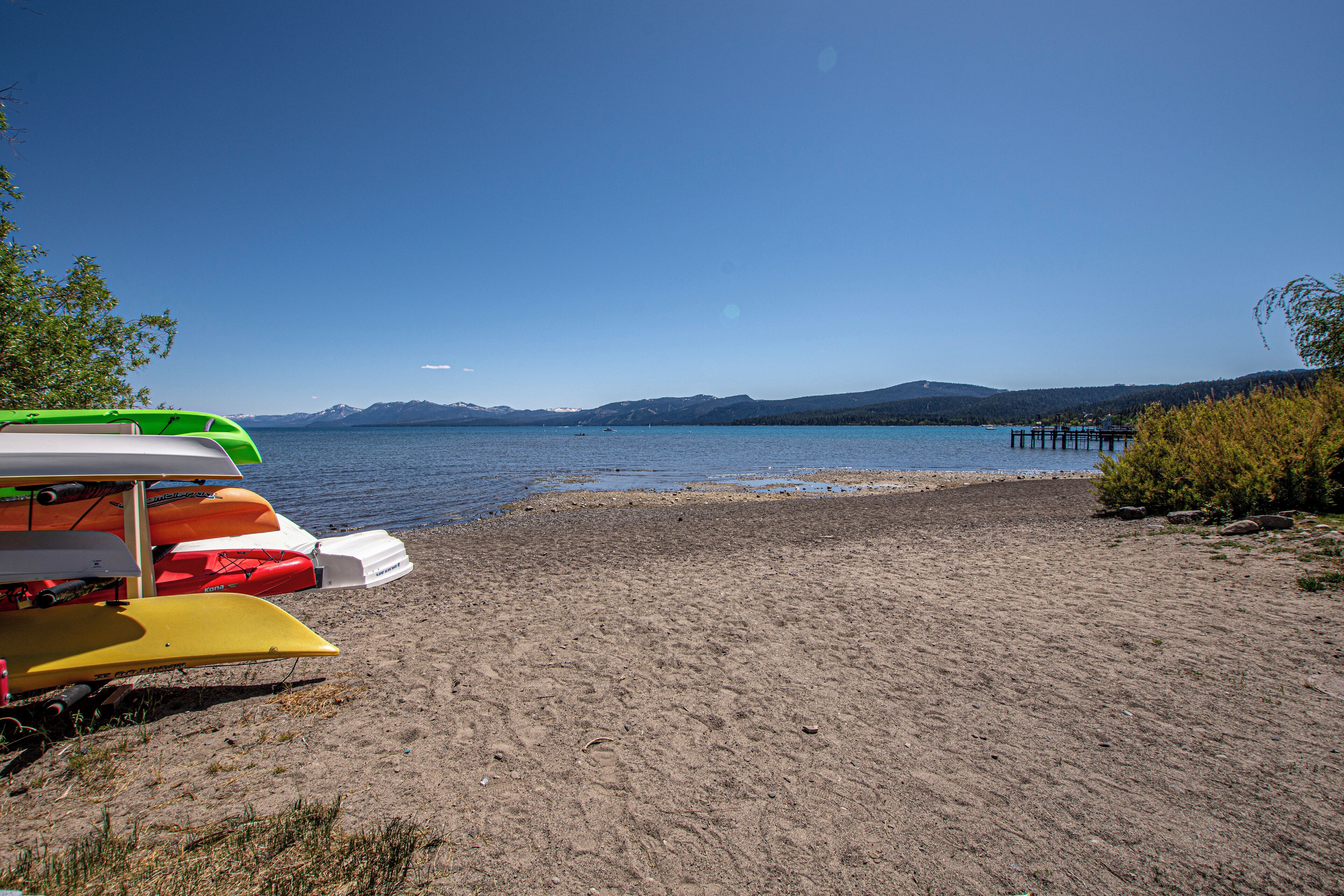 A beach with kayaks and a dock.