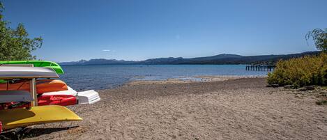 A beach with kayaks and a dock.