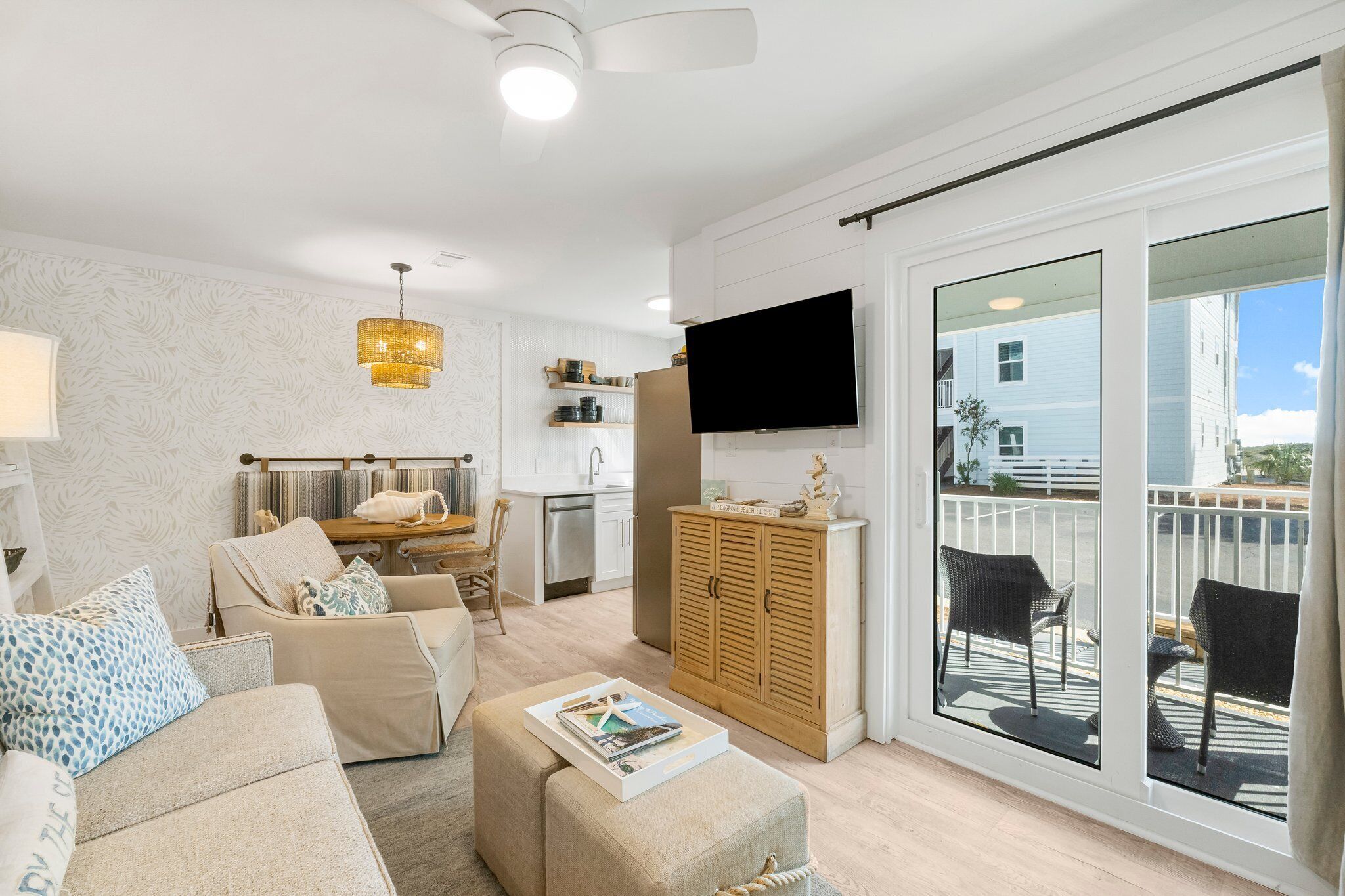 A modern living room with a sofa, ottoman, and a flat-screen TV.