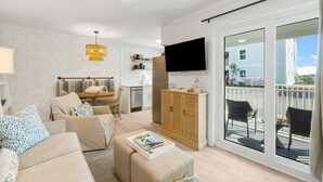 Ein modernes Wohnzimmer mit Sofa, Hocker und Flachbildfernseher.