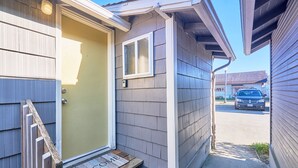Une petite maison de plain-pied, dotée d’une porte d’entrée accueillante et d’un paillasson sur lequel est écrit « BIENVENUE ».