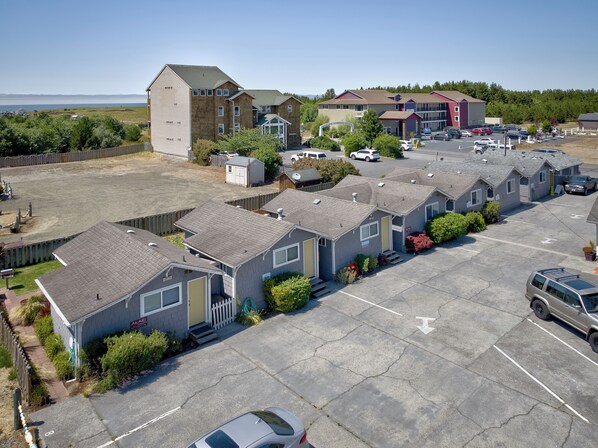 Une rangée de chalets de plain-pied, avec un parking devant.