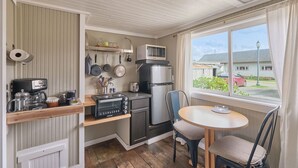 Une cuisine compacte équipée d’un four à micro-ondes, d’un grille-pain et d’une machine à café. Une fenêtre offre une vue sur l’extérieur.