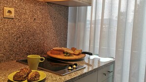 Eine Küche mit Granit-Arbeitsplatten, einem Herd, einem Schneidebrett mit Brot, einer gelben Tasse und einem Teller mit Muffins.