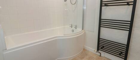 A bathroom with a white bathtub, a glass-enclosed shower, and a black towel rack.