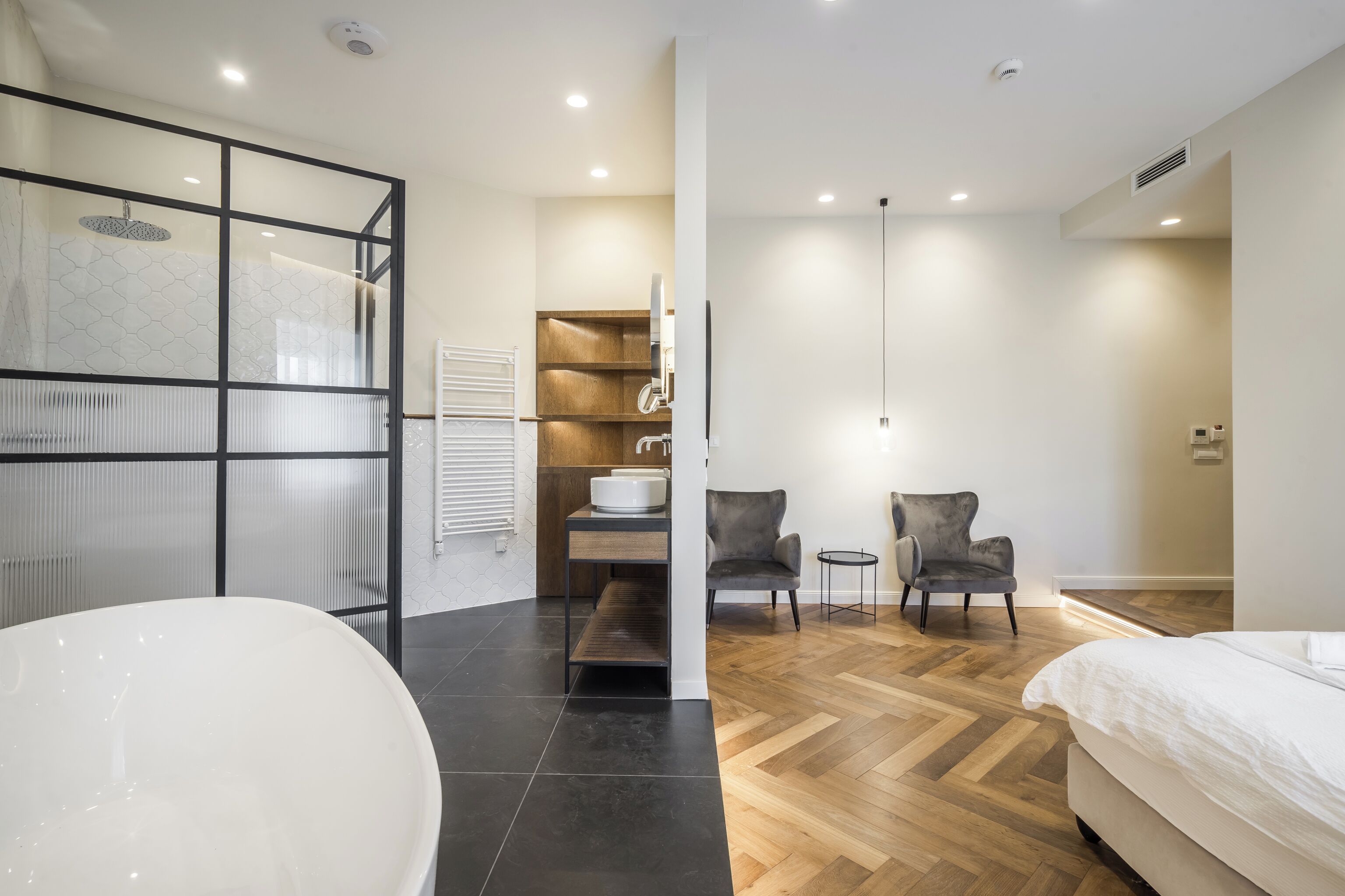 A modern bathroom with a freestanding bathtub, a glass shower enclosure, and a wooden vanity.
