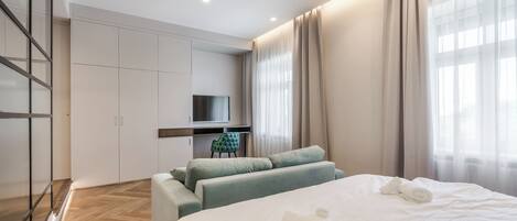A modern hotel room with a large bed, a desk, and a TV.