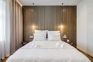 A hotel room with a large bed, two bedside tables, and a wooden slat wall.