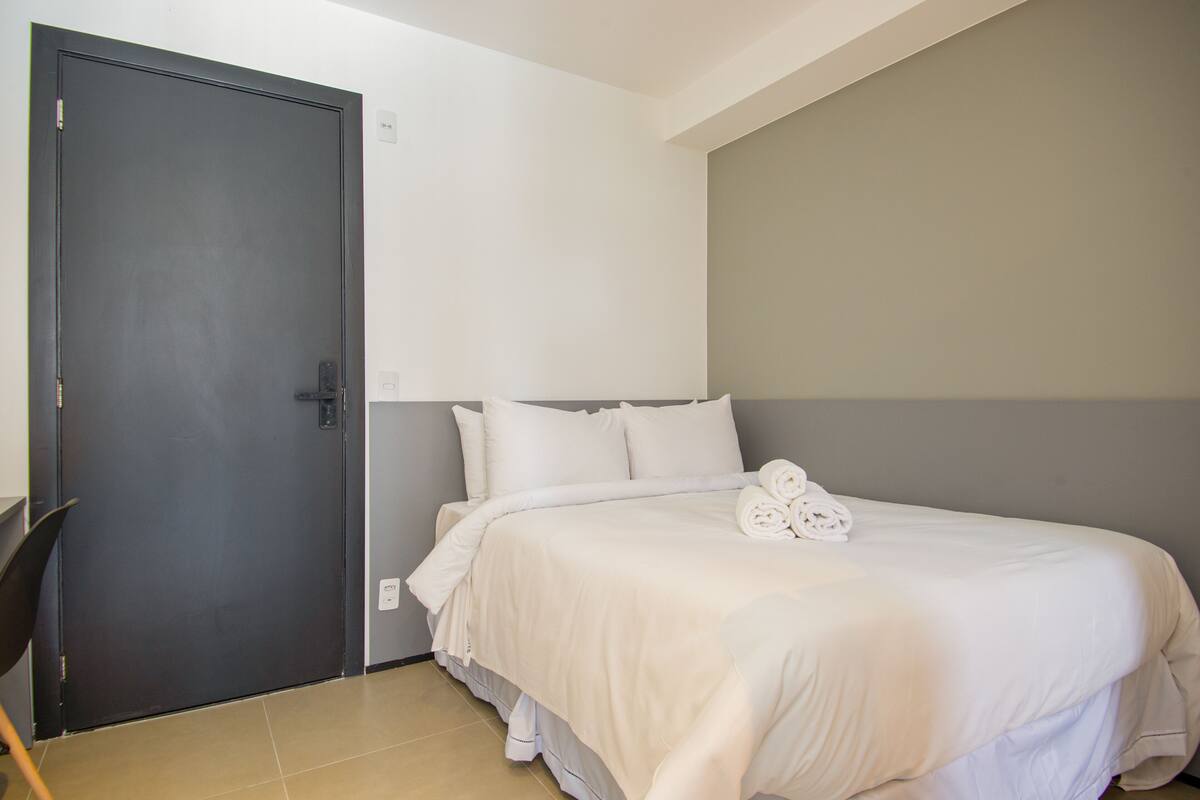Hotellihuone, jossa on sänky, tuoli ja ovi.