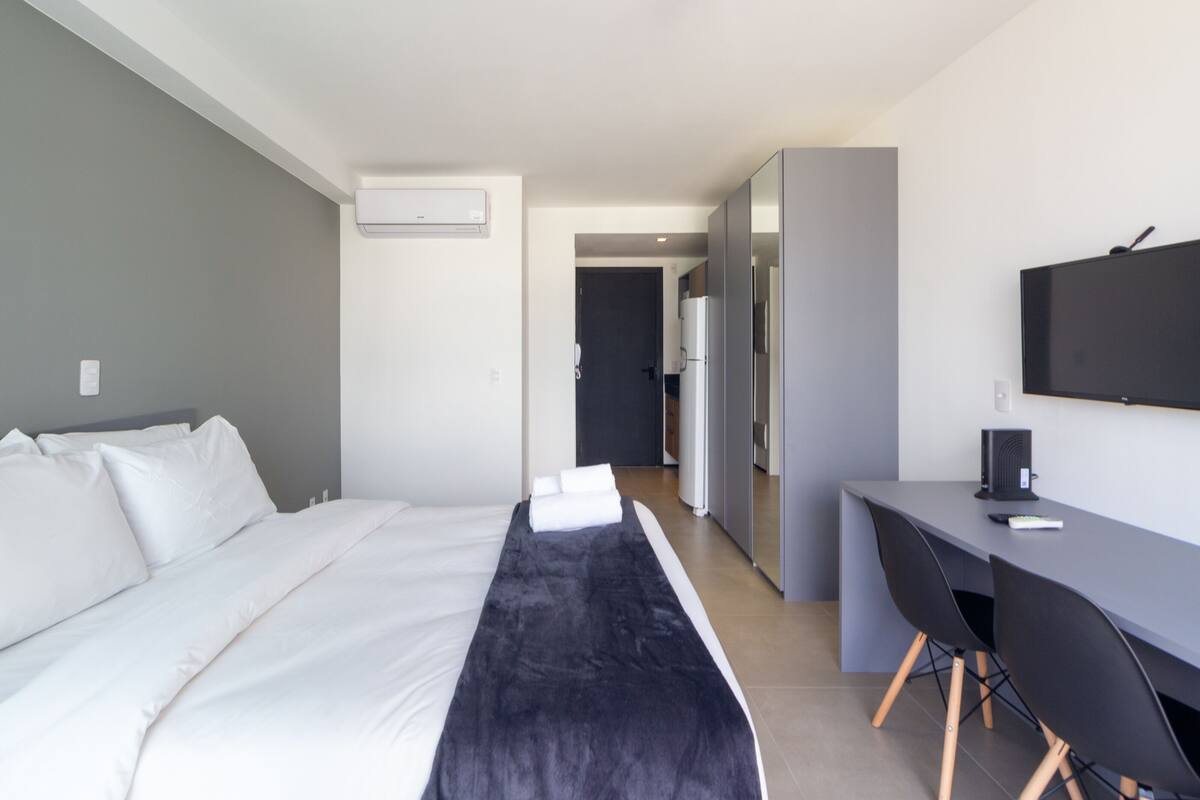 Moderni hotellihuone, jossa on sänky, työpöytä ja televisio.