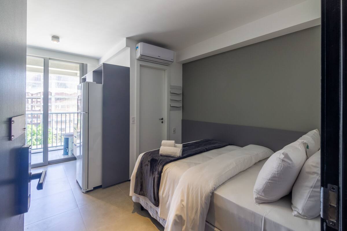 Hotellihuone, jossa on sänky, vaatekaappi, parveke ja ilmastointilaite.