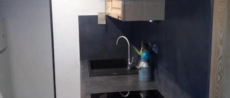 A compact kitchen with a built-in stove, a sink, and wooden cabinets.