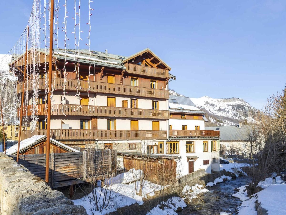 A multi-story wooden building with balconies, a ski lift, and a mountainous backdrop.