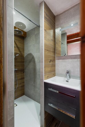 A modern bathroom with a shower, a vanity with a mirror, and a toilet.