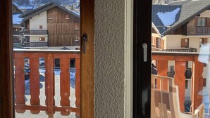 A wooden door with a view of snow-covered mountains and a wooden building with a balcony. - 350m from ski slopes, 3rd floor, balcony, parking, tv, ski locker, 39m², Valloire (Valloire)