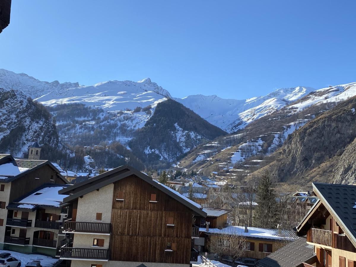 A mountain village with wooden buildings and snow-covered peaks in the background.