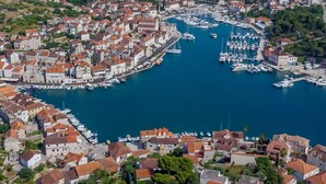 An aerial view of a coastal town with a marina filled with boats, surrounded by residential buildings with red-tiled roofs. - Luxury Villa Essencia Milna Brac with Heated Pool (Milna (Brac))