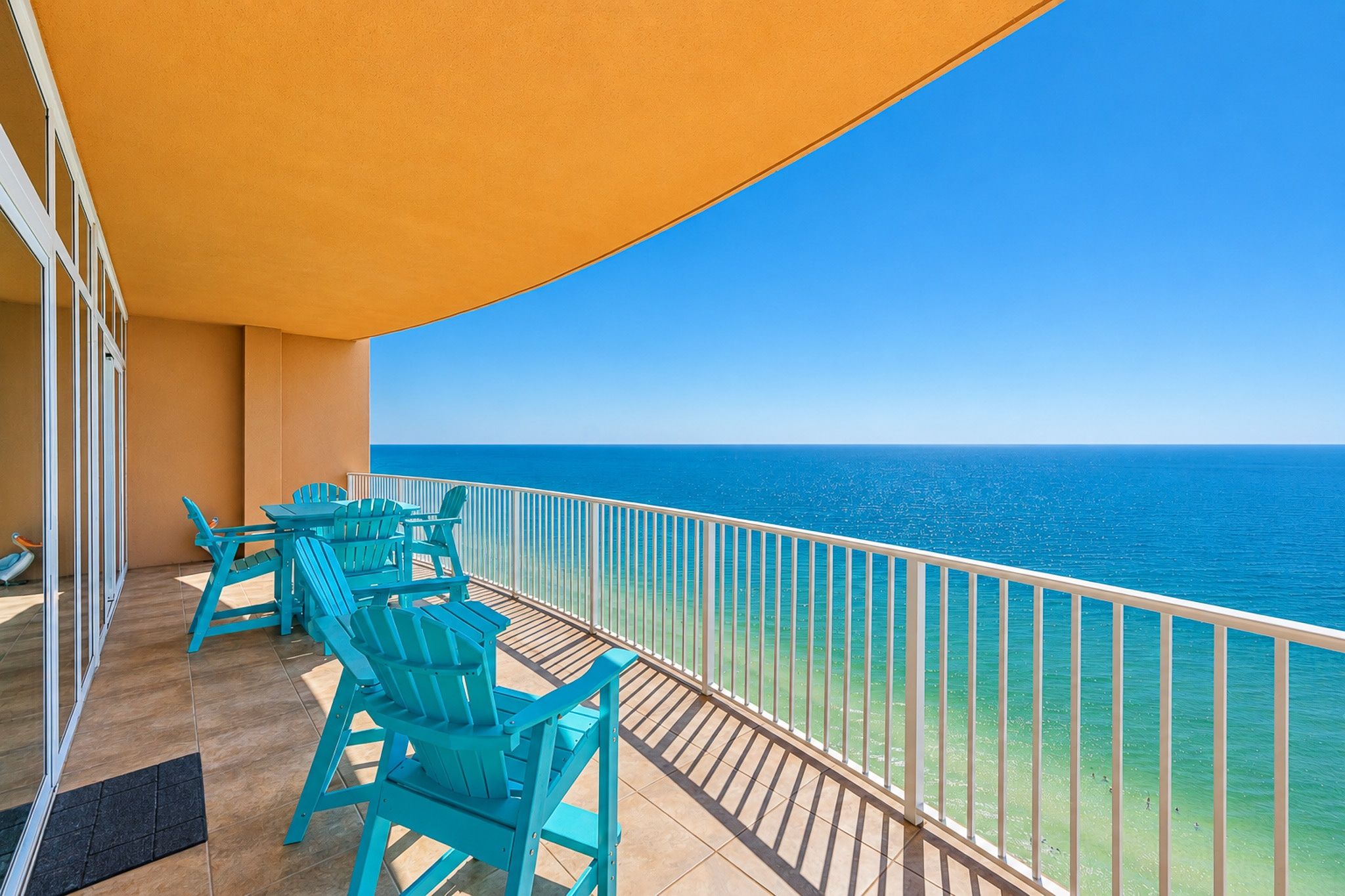 A balcony with turquoise chairs and a view of the ocean.