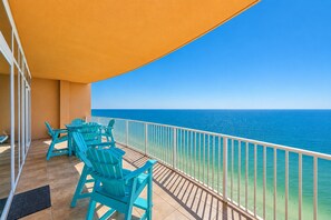 A balcony with turquoise chairs and a view of the ocean.