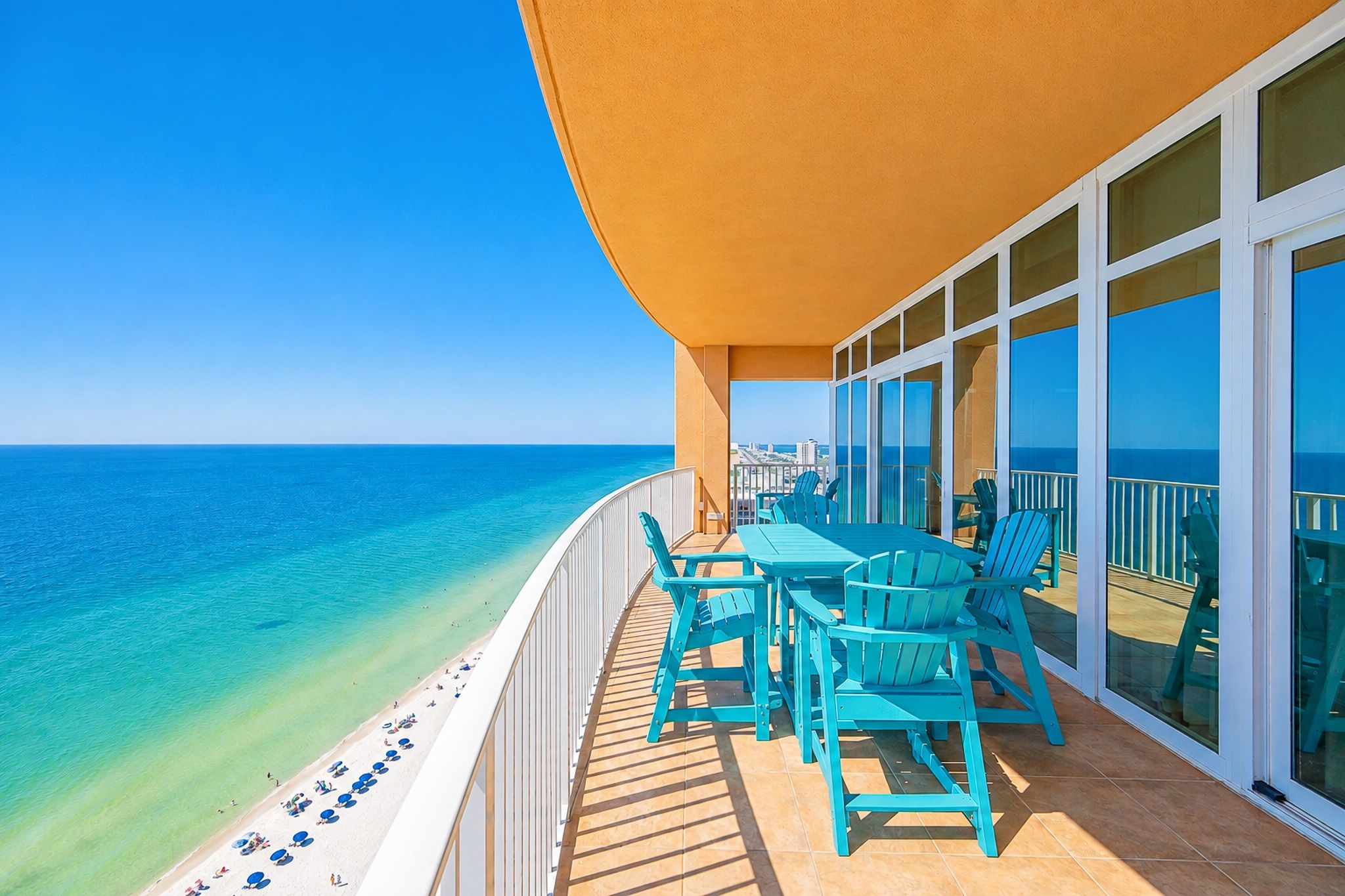 A balcony with a view of the ocean, a table, and chairs.