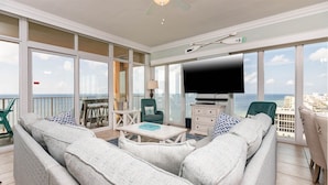 A spacious balcony with a view of the sea, furnished with a sofa, chairs, and a coffee table.