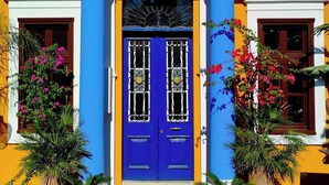 Een gebouw met een blauwe deur, gele muren en decoratieve kolommen.