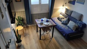 Un espacio habitable compacto con una mesa de comedor, sofá y plantas en macetas.