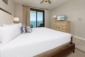Een slaapkamer met een groot bed, een dressoir, een televisie en een balkon met uitzicht.
