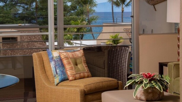 A modern living room with a view of the ocean and palm trees.