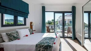 Een hotelkamer met een bed, uitzicht op de omgeving en een balkon met stoelen.