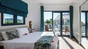 A hotel room with a bed, a view of the outdoors, and a balcony with chairs. - Chez soi Loin de Chez soi (Anse Royale)