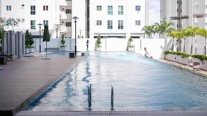 A swimming pool area with a clear view of a high-rise building in the background.