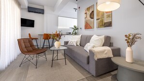 Ein modernes Wohnzimmer mit einem grauen Sofa, einem braunen Ledersessel und einem kleinen runden Tisch.