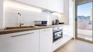 Eine moderne Küche mit weißen Schränken, einer Edelstahl-Spüle und einem Backofen.