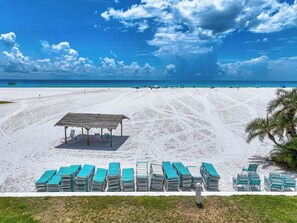 Una playa con un área de descanso techada y filas de sillas reclinables.
