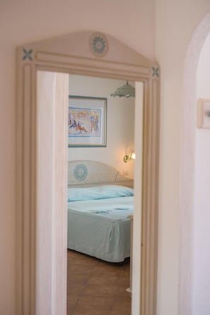 Un dormitorio con cama, una lámpara de pared y un cuadro enmarco.