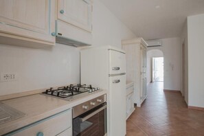 Una cocina con estufa a gas, horno y refrigerador blanco.