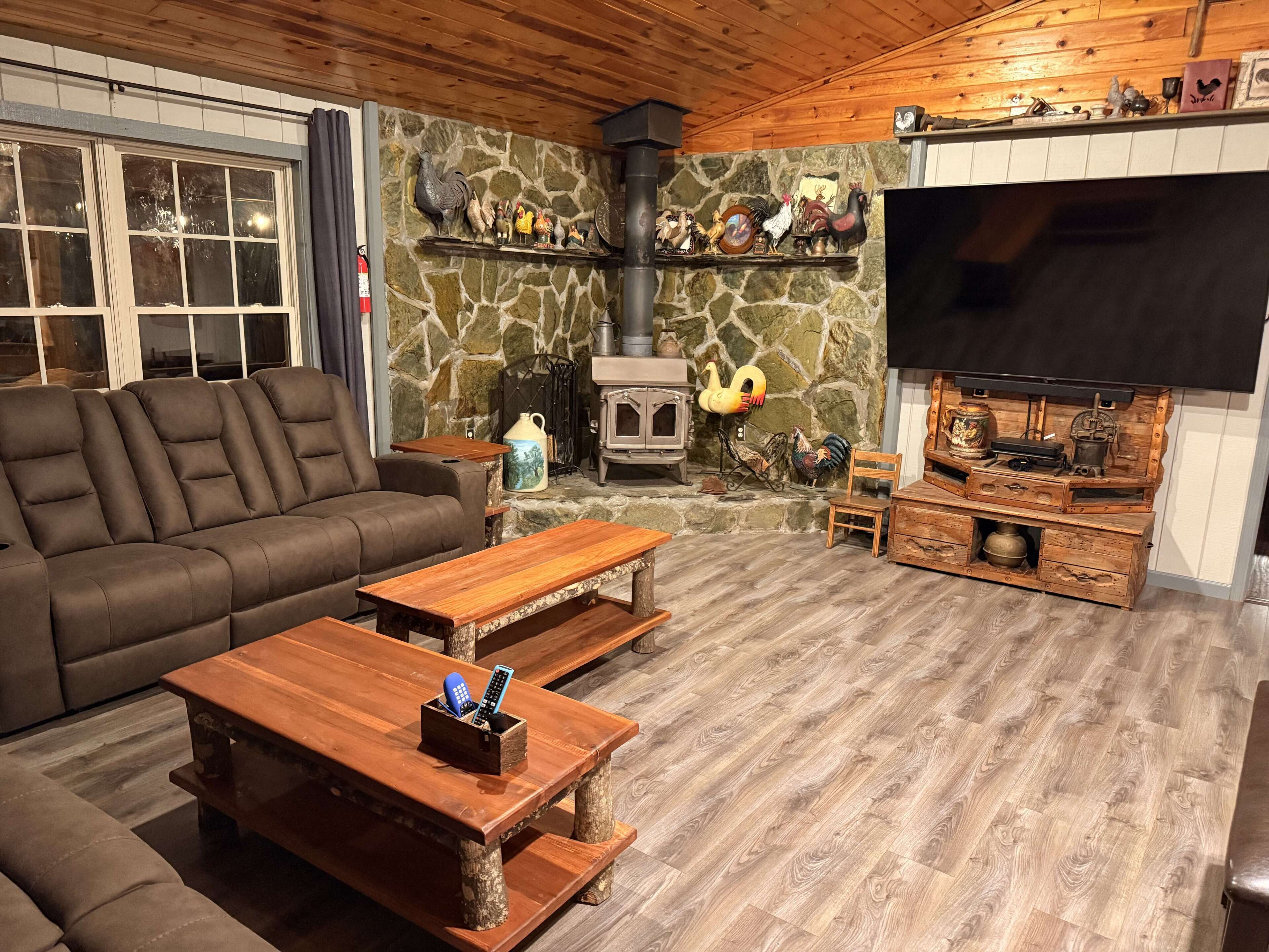A cozy living room with a stone wall, a fireplace, a sofa, a wooden coffee table, and a television.
