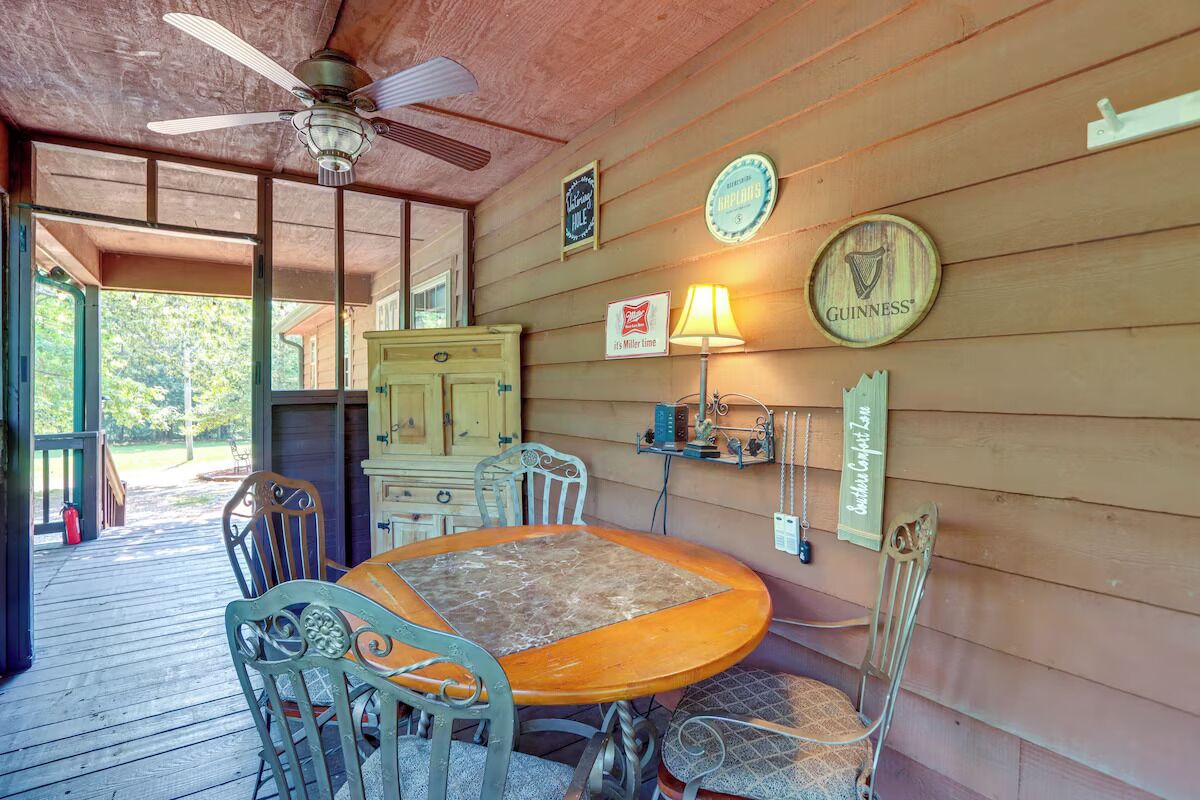 A wooden cabin with a round wooden table and chairs, a ceiling fan, and a sign for Guinness beer.
