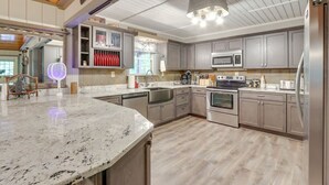 Eine moderne Küche mit Granit Arbeitsplatten, Edelstahlgeräten und Holzböden.