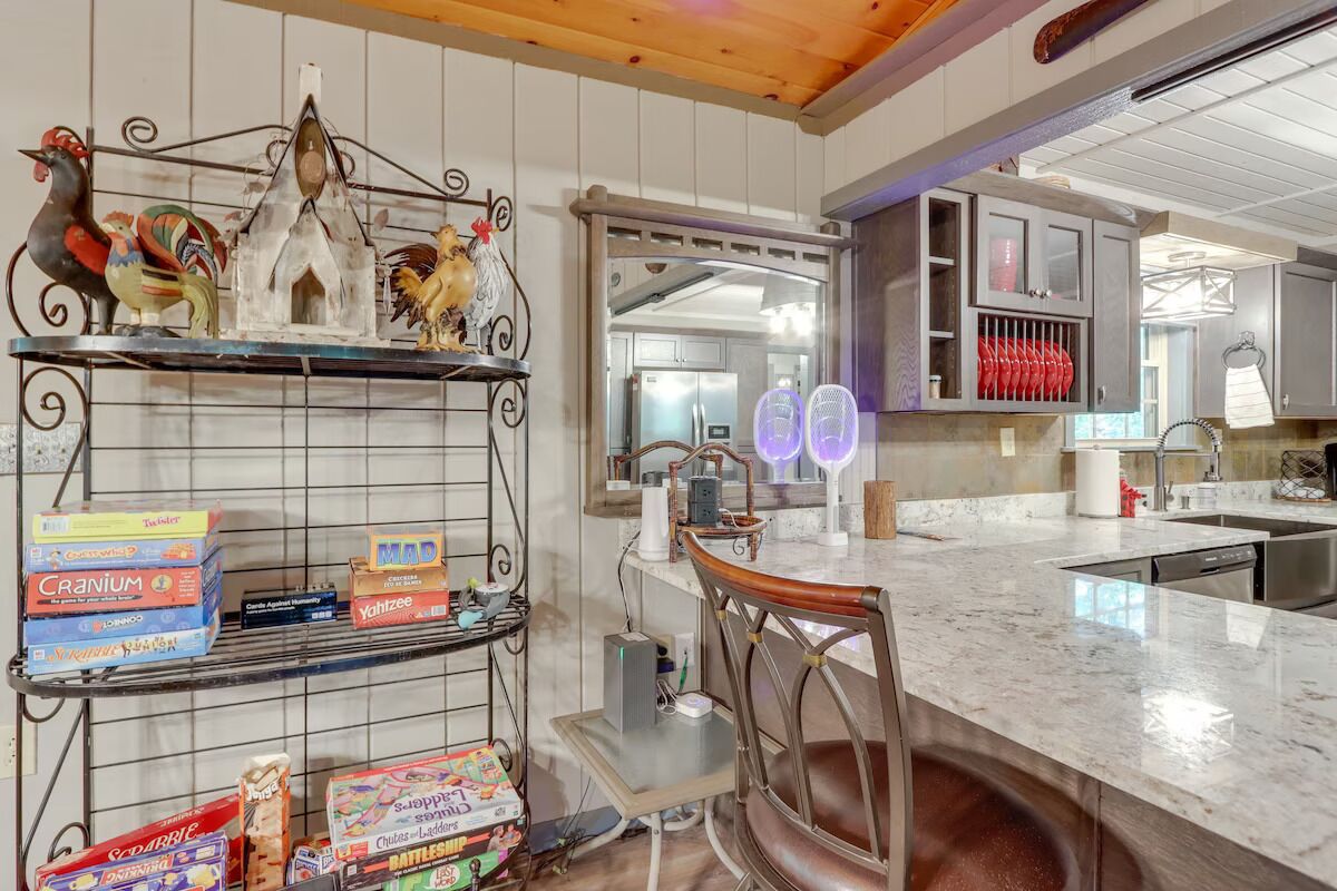 A kitchen with a marble countertop, a bar stool, and shelves with various items.
