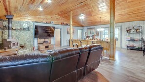Ein geräumiges Wohnzimmer mit einer großen Ledersofa, einem Steinkamin, Holzboden und einer Bar mit Regalen.